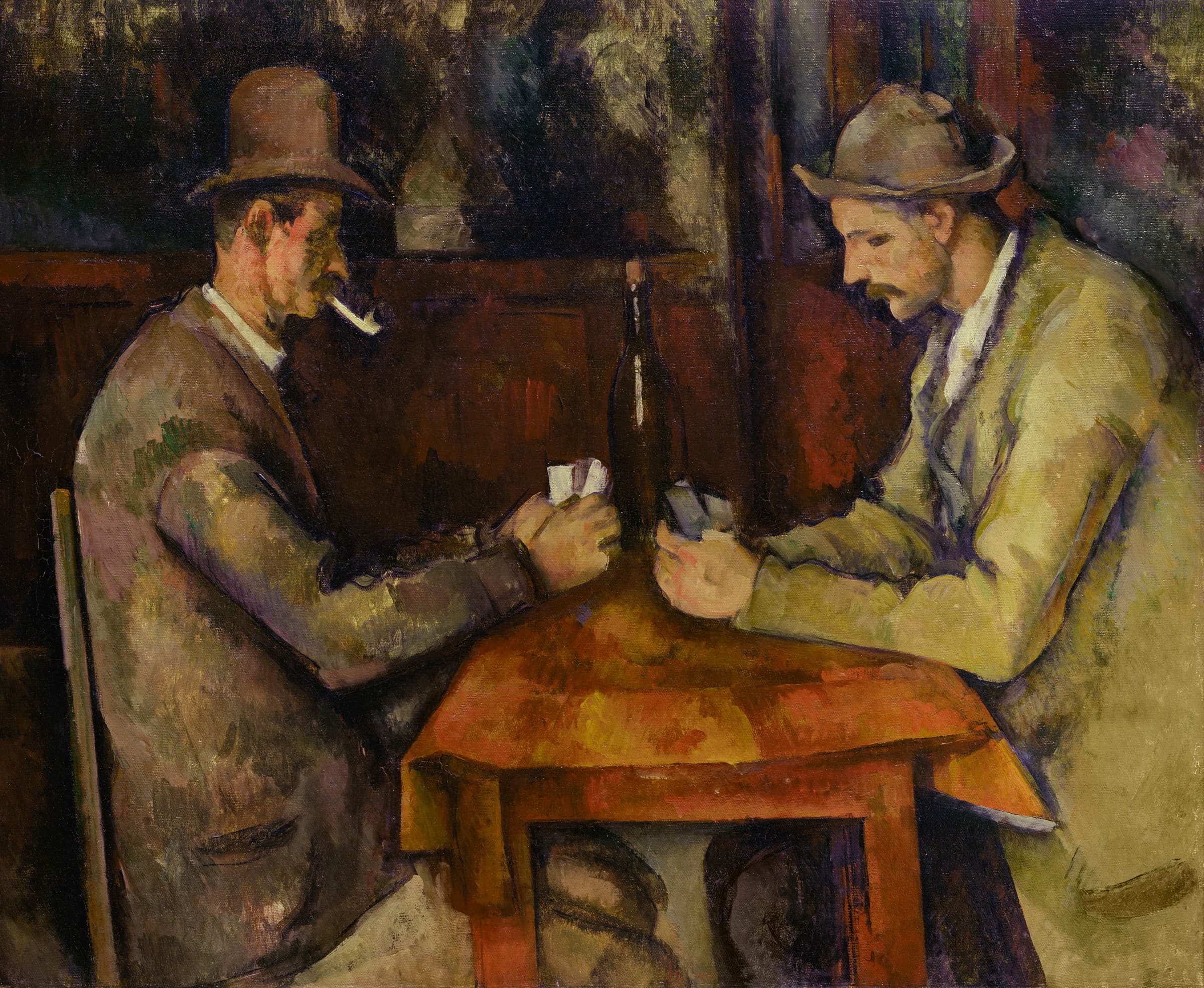 Two men in hats sit across a small table holding their cards, neither one moving